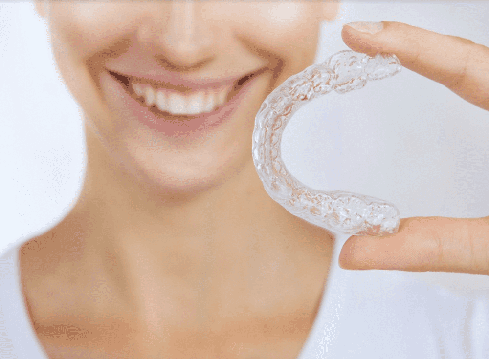 smiling woman holding a clear Invisalign model