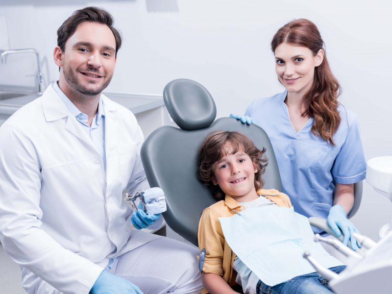 A couple of dentists with a kid in a dentist office